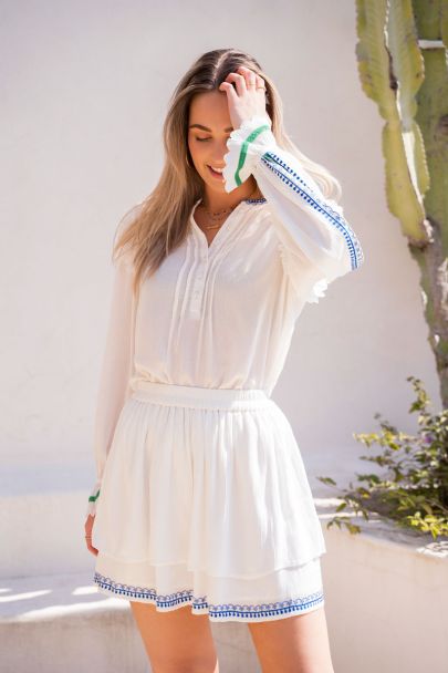 White blouse with blue embroidered hem