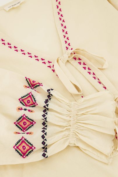 Beigefarbenes Oberteil mit Schleifen und Stickdetails