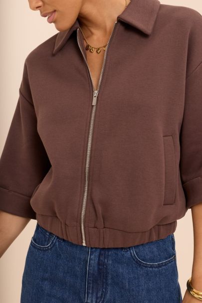 Brown sweater vest with rolled-up sleeves