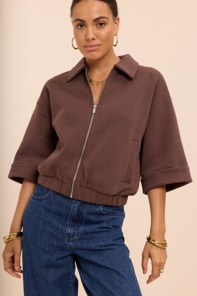 Brown sweater vest with rolled-up sleeves